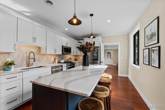 1824 Topping Rd, Saint Louis, MO 63131 - kitchen featuring appliances with stainless steel finishes, a sink, tasteful backsplash, a kitchen island, and a kitchen bar