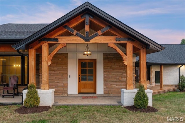 1824 Topping Rd, Saint Louis, MO 63131 - exterior entry at dusk with stone siding, roof with shingles, and covered porch