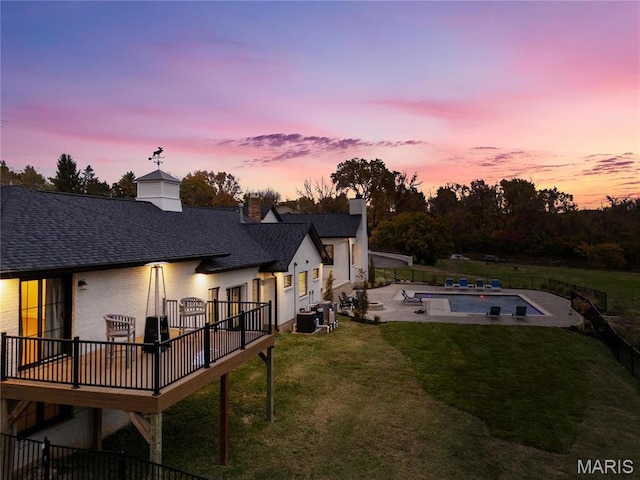 1824 Topping Rd, Saint Louis, MO 63131 - back of house at dusk featuring a deck, central AC unit, roof with shingles, a patio area, and a chimney