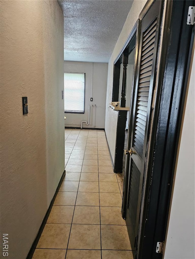 12 Agnes Dr, Cahokia, IL 62206 - hallway featuring a textured wall, a textured ceiling, light tile patterned flooring, and radiator heating unit