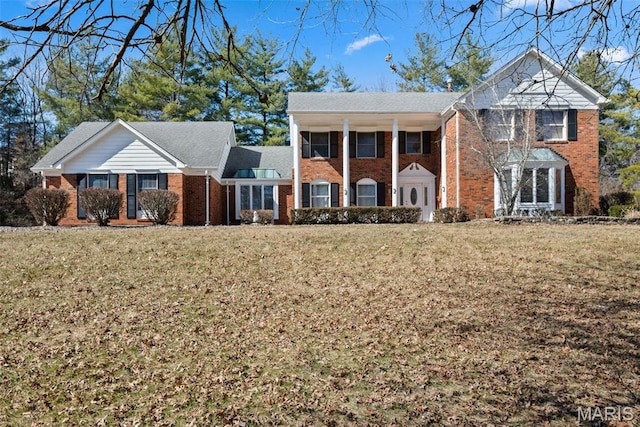 greek revival house featuring brick siding and a front lawn