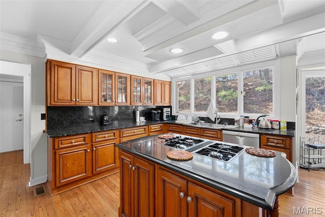 kitchen with appliances with stainless steel finishes, brown cabinets, light wood-type flooring, tasteful backsplash, and ornamental molding