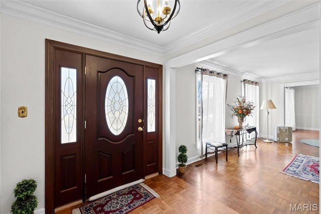 foyer entrance featuring a chandelier, baseboards, and ornamental molding
