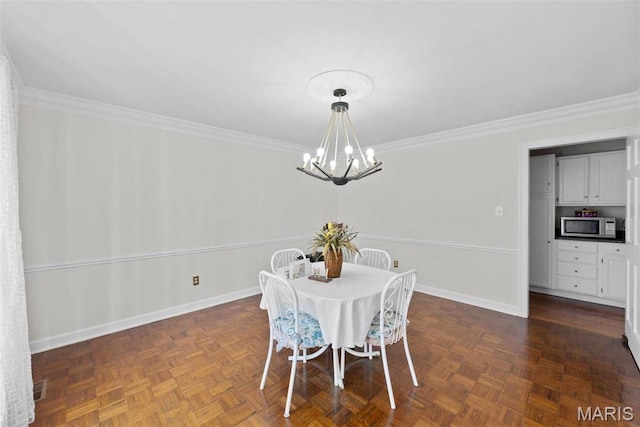 dining space featuring a chandelier, ornamental molding, and baseboards