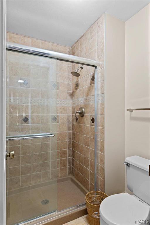 full bath with a stall shower, toilet, and tile patterned flooring