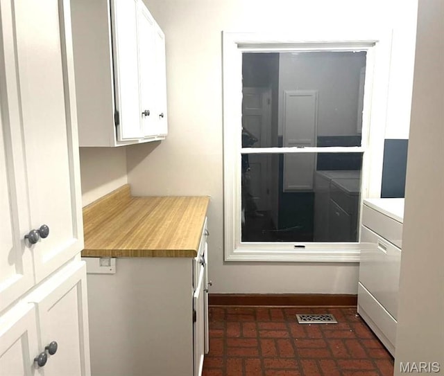 laundry room featuring brick flooring, baseboards, and separate washer and dryer