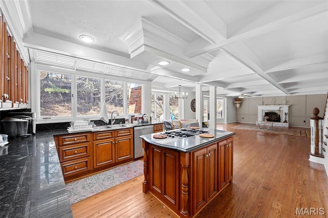 kitchen featuring a sink, stainless steel appliances, brown cabinetry, a fireplace, and coffered ceiling