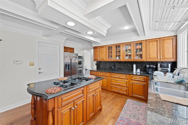 kitchen featuring stainless steel appliances, a sink, brown cabinetry, coffered ceiling, and tasteful backsplash