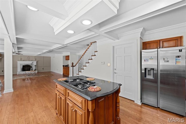 kitchen with stainless steel refrigerator with ice dispenser, black gas cooktop, a brick fireplace, light wood finished floors, and coffered ceiling