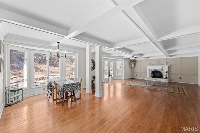 living room with coffered ceiling, a fireplace, light wood-style flooring, a chandelier, and baseboards
