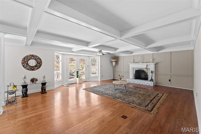 unfurnished living room with coffered ceiling, hardwood / wood-style flooring, ceiling fan, beam ceiling, and a brick fireplace