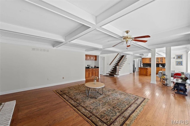 living area featuring coffered ceiling, light wood finished floors, a ceiling fan, baseboards, and beam ceiling