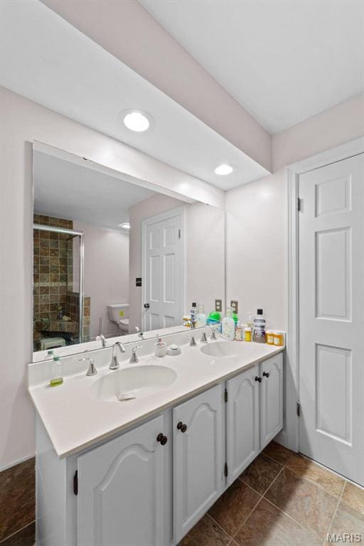 bathroom featuring toilet, a stall shower, double vanity, and recessed lighting