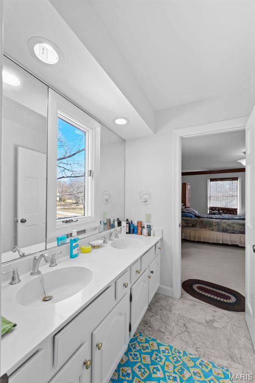 ensuite bathroom with double vanity and marble finish flooring