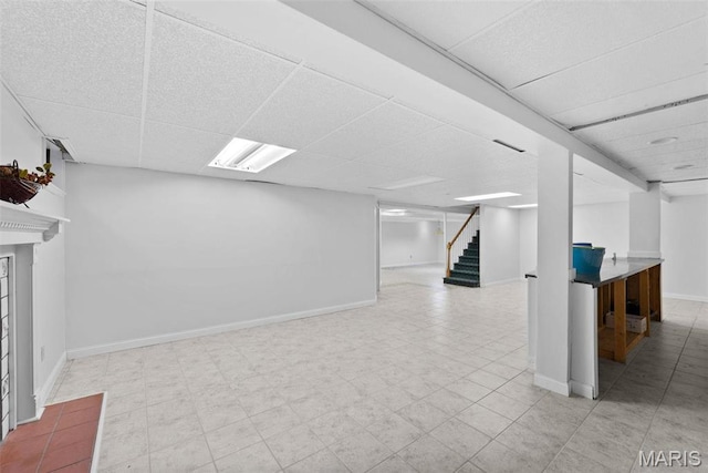 finished below grade area with a drop ceiling, stairs, and baseboards
