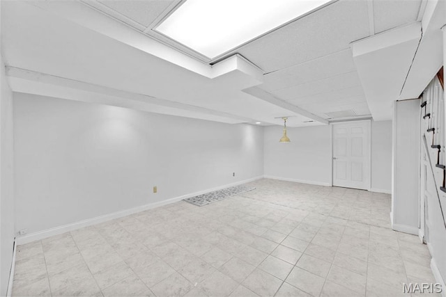 finished basement featuring baseboards and light flooring