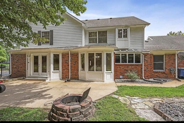 back of house featuring a patio, an outdoor fire pit, brick siding, french doors, and roof with shingles