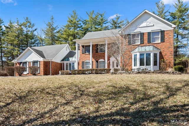 neoclassical home featuring brick siding and a front lawn