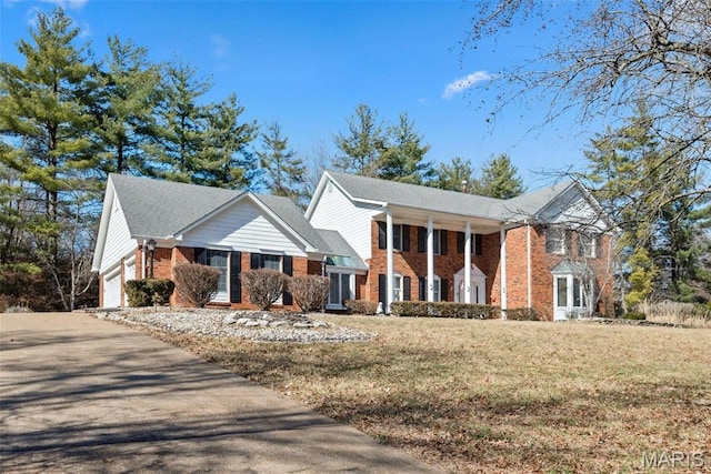 view of front of house with brick siding, a garage, a front lawn, and driveway