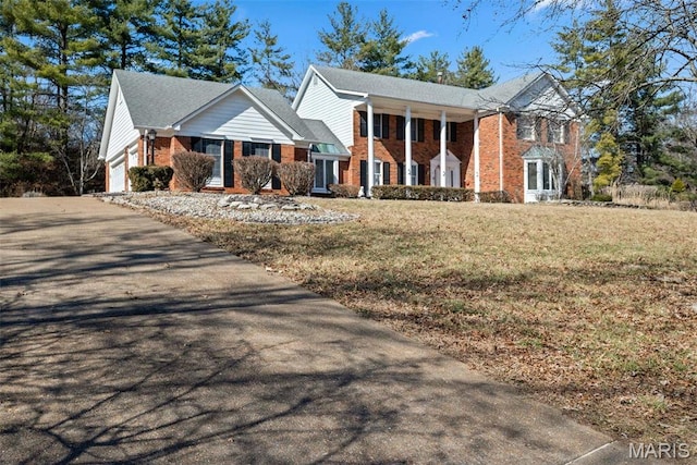 neoclassical home with brick siding, asphalt driveway, and a front yard