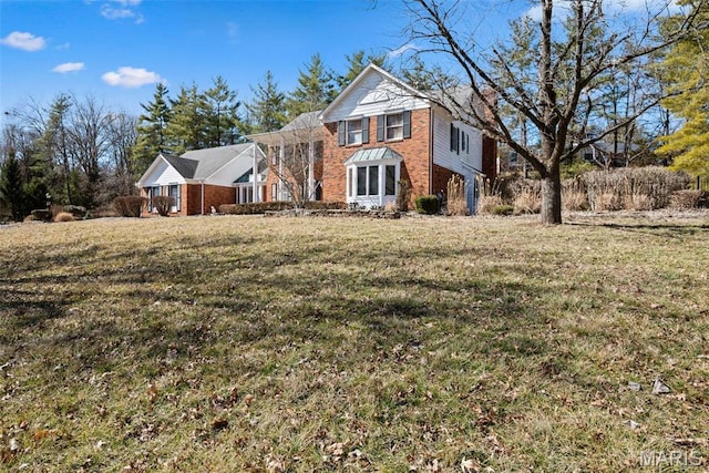 traditional-style home featuring brick siding and a front yard