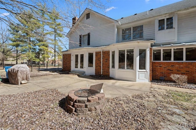 rear view of house featuring brick siding, french doors, a chimney, and fence