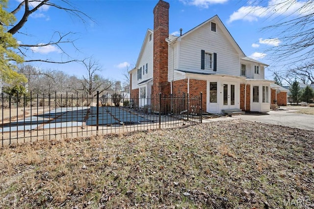 rear view of house featuring brick siding, french doors, fence, and a patio area