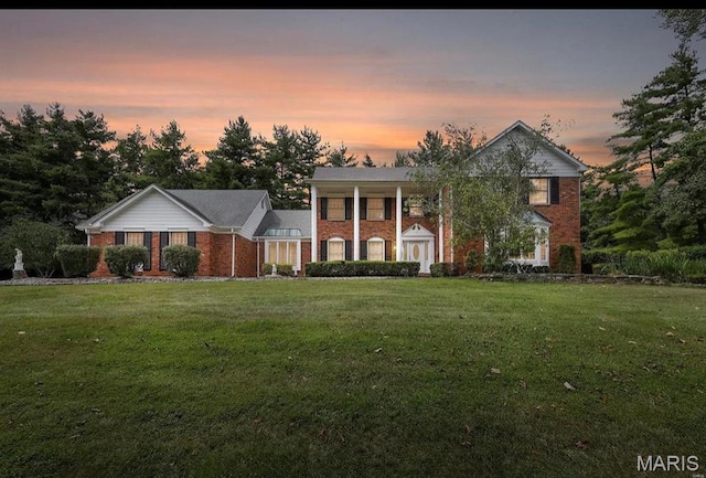neoclassical home featuring a front lawn and brick siding