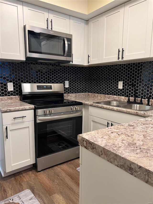 7100 Lexington Ave, Saint Louis, MO 63121 - kitchen featuring stainless steel appliances, a sink, wood finished floors, and white cabinets