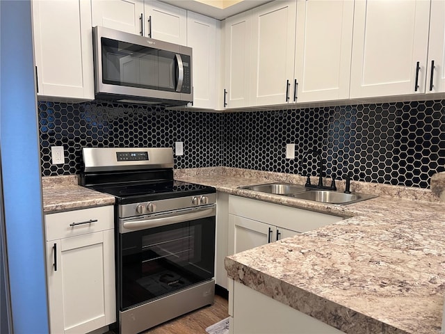 7100 Lexington Ave, Saint Louis, MO 63121 - kitchen featuring stainless steel appliances, decorative backsplash, a sink, and white cabinets
