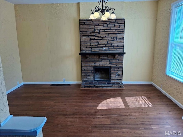 2709 Keokuk St, Saint Louis, MO 63118 - unfurnished living room with a chandelier, wood finished floors, a fireplace, baseboards, and a textured wall