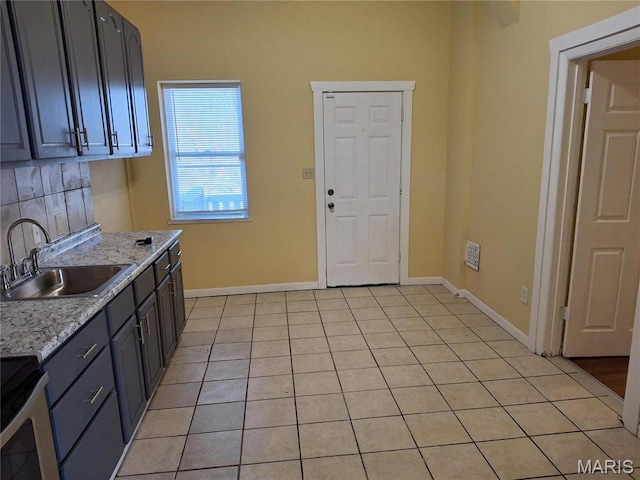 2709 Keokuk St, Saint Louis, MO 63118 - kitchen with a sink, stove, light tile patterned flooring, baseboards, and tasteful backsplash