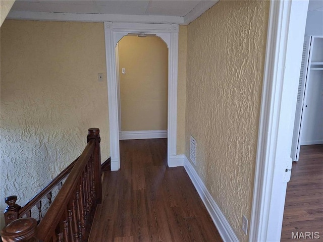 2709 Keokuk St, Saint Louis, MO 63118 - hallway featuring a textured wall, wood finished floors, an upstairs landing, arched walkways, and baseboards