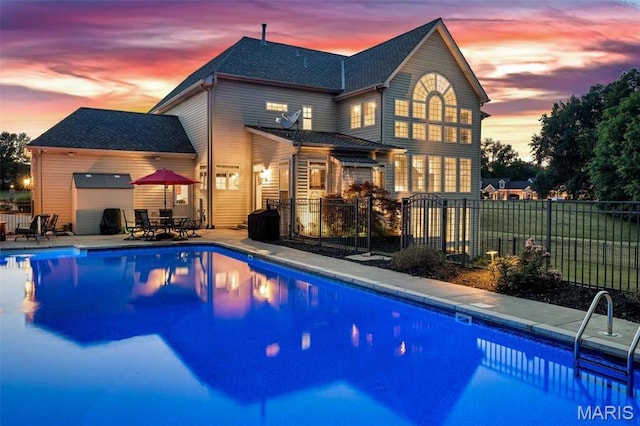244 US Dr, Wentzville, MO 63385 - back of property at dusk with fence, a shingled roof, a garage, and a patio