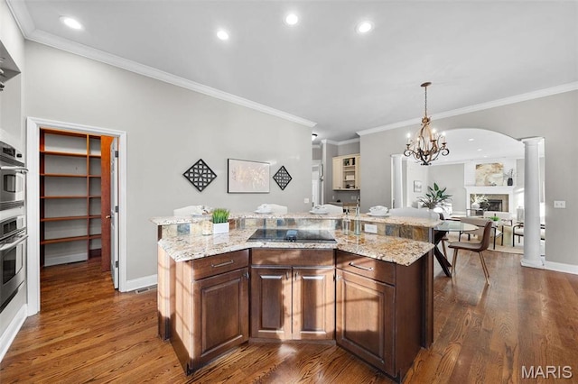 244 US Dr, Wentzville, MO 63385 - kitchen with black electric cooktop, ornamental molding, dark wood-type flooring, a fireplace, and a center island