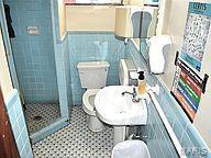6817 Gravois Ave, Saint Louis, MO 63116 - bathroom featuring a stall shower, toilet, a wainscoted wall, and tile walls