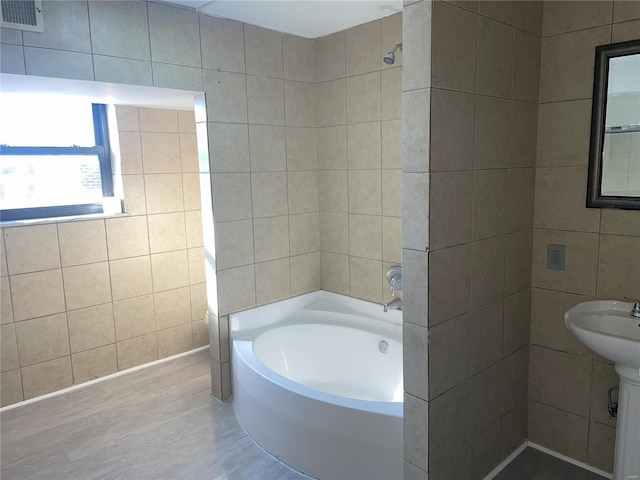 6817 Gravois Ave, Saint Louis, MO 63116 - bathroom featuring tile walls, a bath, and wood finished floors