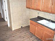 6817 Gravois Ave, Saint Louis, MO 63116 - washroom with wood finished floors, a sink, and tile walls