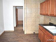 6817 Gravois Ave, Saint Louis, MO 63116 - kitchen with brown cabinetry, dark wood-type flooring, baseboards, and dark countertops