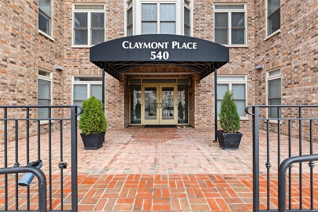 view of exterior entry featuring french doors and brick siding