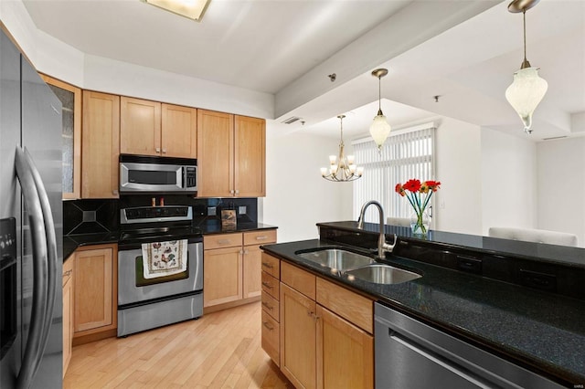 kitchen with stainless steel appliances, a sink, a chandelier, light wood-style floors, and decorative light fixtures
