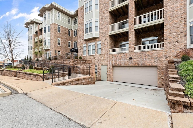 view of apartment building / complex with a garage and concrete driveway