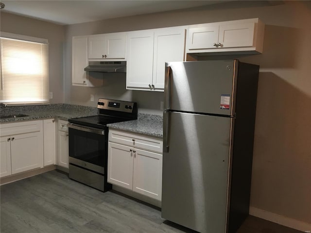 2812 Annapolis Ave, Saint Louis, MO 63114 - kitchen featuring stainless steel appliances, under cabinet range hood, white cabinets, light wood finished floors, and light stone counters