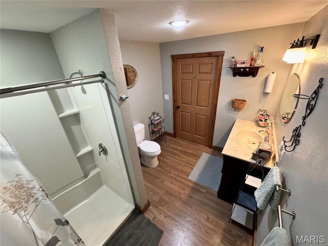 301 W Summer St, Monroe City, MO 63456 - full bathroom with wood finished floors, a shower stall, toilet, vanity, and a textured wall