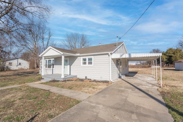 121 W Hicks St, Cardwell, MO 63829 - bungalow-style house with covered porch, driveway, an attached carport, a shingled roof, and a front yard