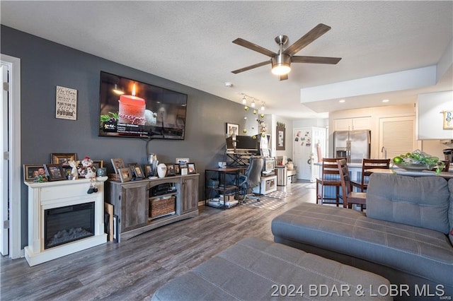 living room featuring ceiling fan, wood finished floors, a glass covered fireplace, a desk, and recessed lighting