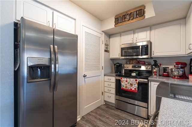 kitchen featuring appliances with stainless steel finishes, white cabinets, dark wood-type flooring, and light countertops