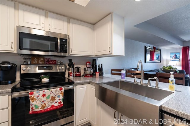 kitchen featuring stainless steel appliances, a sink, white cabinets, and light countertops