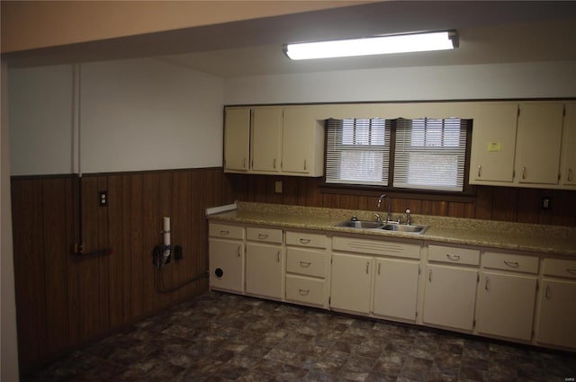25 N 44th St, Belleville, IL 62226 - kitchen featuring a sink, wood walls, a wainscoted wall, white cabinetry, and stone finish floors