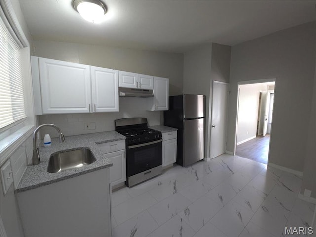 10468 Halls Ferry Rd, Saint Louis, MO 63136 - kitchen with gas stove, freestanding refrigerator, under cabinet range hood, a sink, and white cabinetry